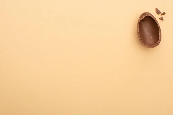 Vista superior de huevo de chocolate medio sobre fondo beige - foto de stock