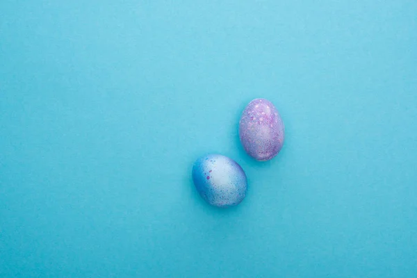 Vista dall'alto di uova di pollo colorate su sfondo blu — Foto stock