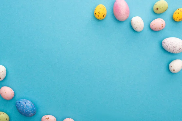 Top view of colorful painted chicken and quail eggs on blue background — Stock Photo