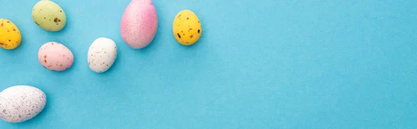 Vue de dessus des oeufs de poulet et de caille peints colorés sur fond bleu, vue panoramique — Photo de stock