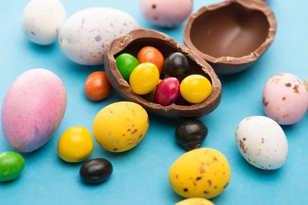 Close up of Easter chicken, quail and chocolate eggs with candies on blue background — Stock Photo