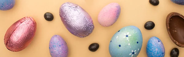 Vue du dessus des œufs de Pâques en chocolat avec des bonbons et des œufs de caille sur fond beige, vue panoramique — Photo de stock