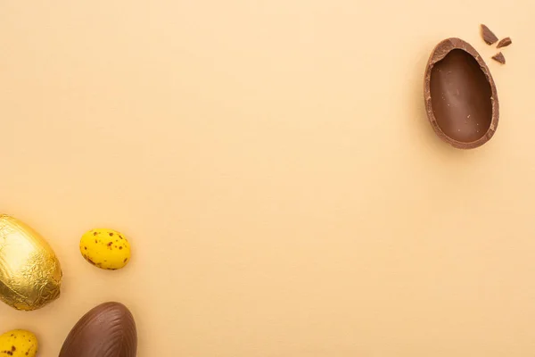 Vue de dessus des oeufs de Pâques en caille jaune et chocolat sur fond beige — Photo de stock