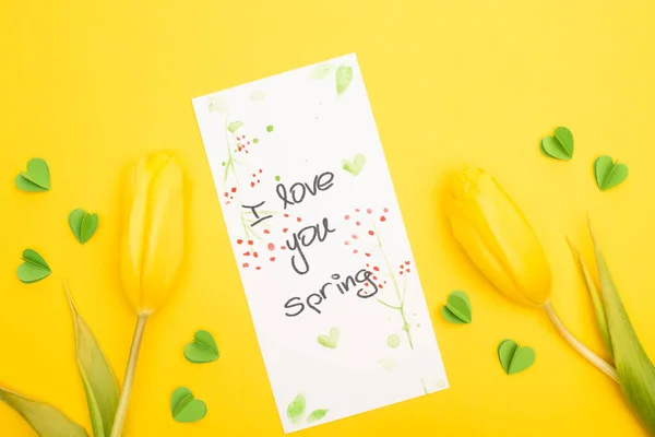 Vista superior de tulipas, cartão com eu te amo letras primavera e corações decorativos no fundo amarelo — Fotografia de Stock