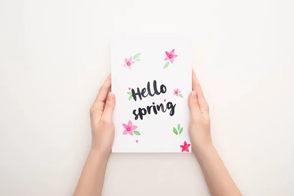 Vista ritagliata di donna in possesso di carta con scritte ciao primavera su sfondo bianco — Foto stock