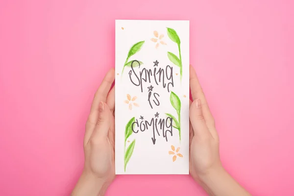 Partial view of woman holding card with spring is coming lettering on pink — Stock Photo