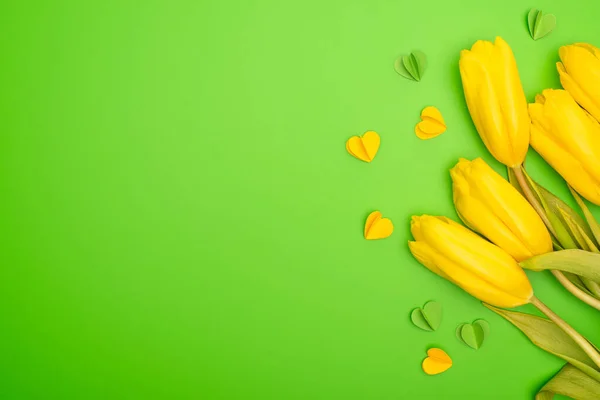 Vue du dessus des tulipes jaunes et des cœurs décoratifs sur le vert, concept printemps — Photo de stock