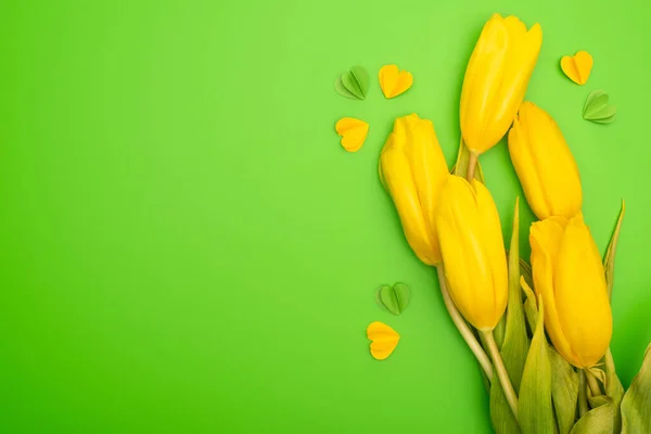 Vista superior de tulipas amarelas e corações decorativos coloridos em verde, conceito de primavera — Fotografia de Stock