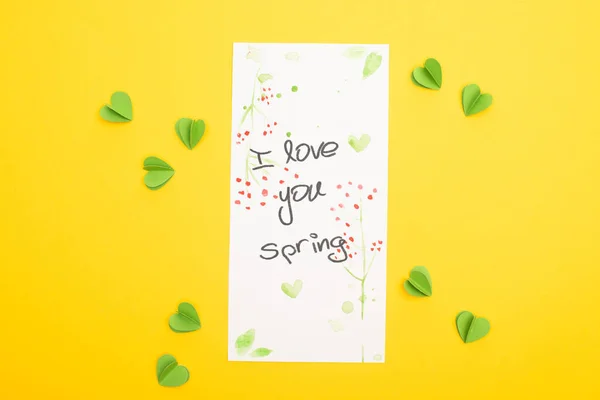 Top view of card with I love you spring lettering and decorative green hearts on yellow background — Stock Photo