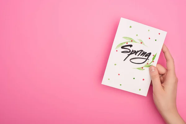 Cropped view of woman holding card with spring lettering on pink background — Stock Photo