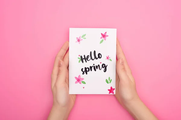 Ausgeschnittene Ansicht einer Frau mit Karte mit Hallo-Frühling-Schriftzug auf rosa — Stockfoto