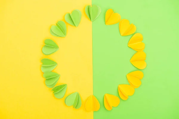 Draufsicht auf dekorative Herzen auf gelbem und grünem Hintergrund, Frühlingskonzept — Stockfoto