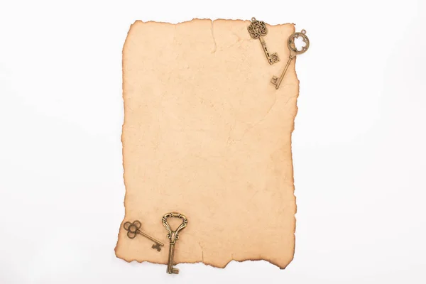 Vue de dessus des clés vintage sur papier vieilli isolé sur blanc — Photo de stock