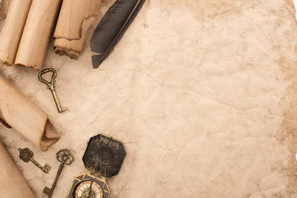 Top view of vintage keys and compass near feather on aged paper — Stock Photo