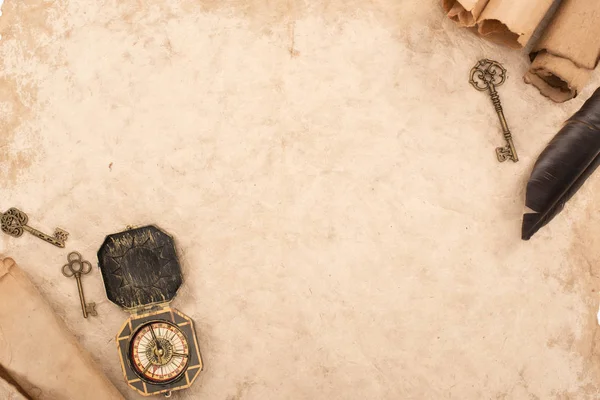 Вид сверху на перо, винтажные ключи и компас на старой бумаге — стоковое фото