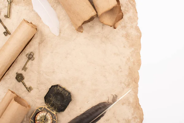 Верхний вид перьев, винтажных ключей и компаса на старой бумаге, изолированной на белом — стоковое фото
