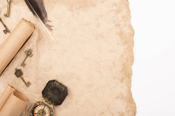 Top view of feather, vintage keys and compass on aged paper isolated on white — Stock Photo