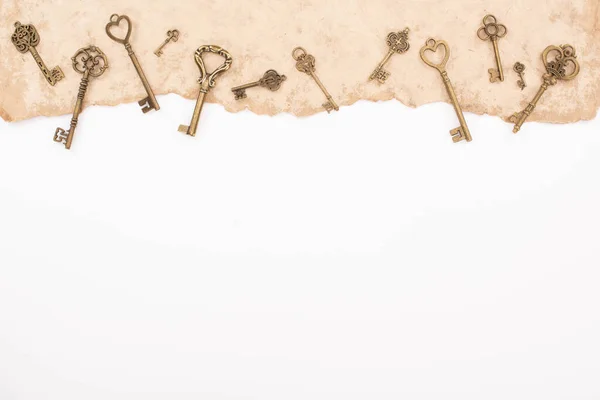 Top view of vintage keys on aged paper isolated on white — Stock Photo