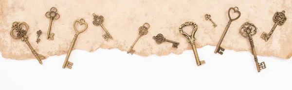 Top view of vintage keys on aged paper isolated on white, panoramic shot — Stock Photo