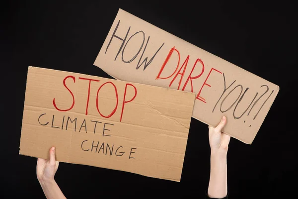 Vue croustillante d'une femme tenant des pancartes avec comment oser et arrêter le lettrage sur le changement climatique isolé sur le concept noir de réchauffement planétaire — Photo de stock
