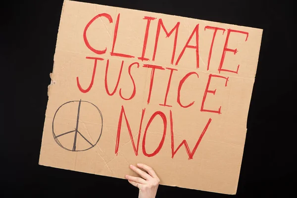 Partial view of woman holding placard with climate justice now lettering isolated on black, global warming concept — Stock Photo