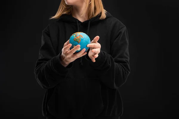 Vista recortada de la mujer sosteniendo globo de plastilina aislado en negro, concepto de calentamiento global - foto de stock