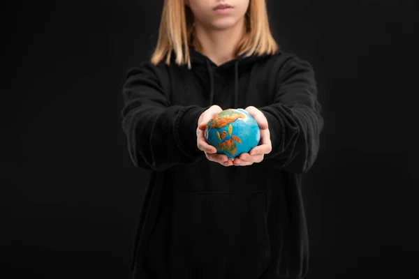 Partial view of woman with outstretched hands holding plasticine globe isolated on black, global warming concept — Stock Photo