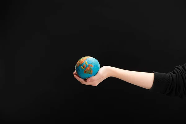 Vista parcial de la mujer con la mano extendida sosteniendo globo de plastilina aislado en negro, concepto de calentamiento global - foto de stock