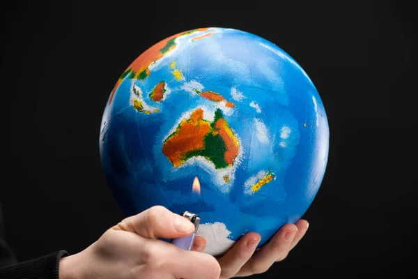 Cropped view of woman holding lighter and globe isolated on black, global warming concept — Stock Photo