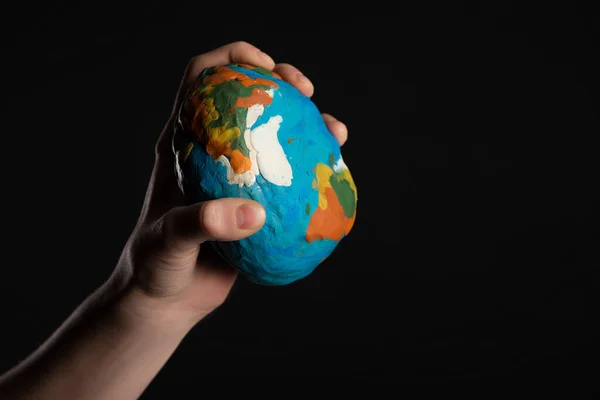 Cropped view of plasticine globe in female hand isolated on black, global warming concept — Stock Photo