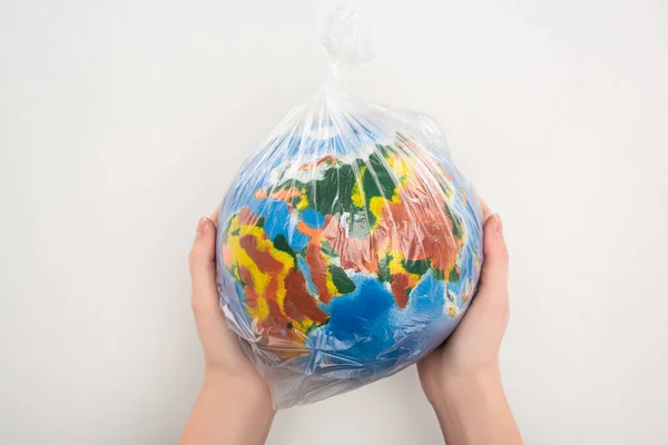 Обрізаний вид жінки, що тримає поліетиленовий пакет з глобусом на білому, концепція глобального потепління — стокове фото