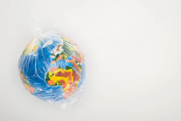 Vista superior del globo en bolsa de plástico sobre fondo blanco, concepto de calentamiento global - foto de stock