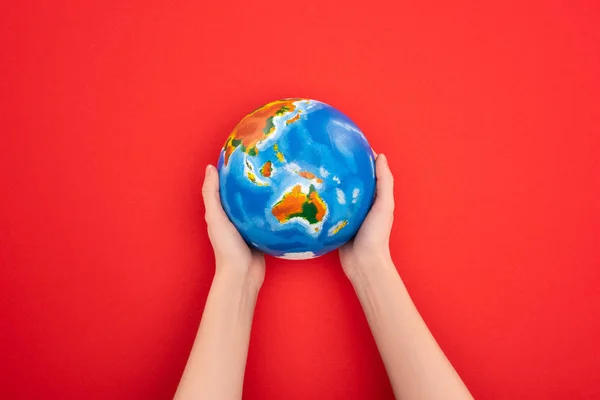 Vista recortada de la mujer sosteniendo globo sobre fondo rojo, concepto de calentamiento global - foto de stock