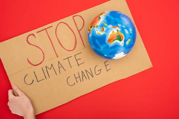 Ausgeschnittene Ansicht einer Frau mit Plakat mit Stop-Klimawandel-Schriftzug und Globus auf rotem, globalem Erwärmungskonzept — Stockfoto