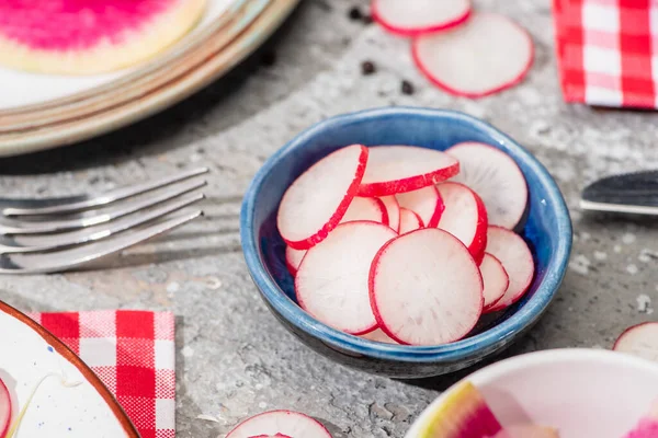 Close up view of fresh radish slices in bowl on grey concrete surface — Stock Photo