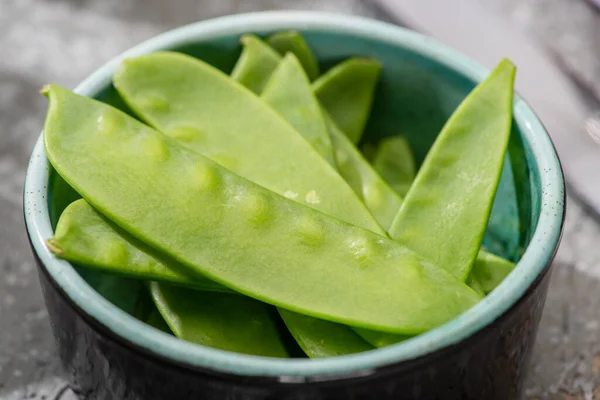 Close up view of fresh green pea in bowl on grey concrete surface — Stock Photo