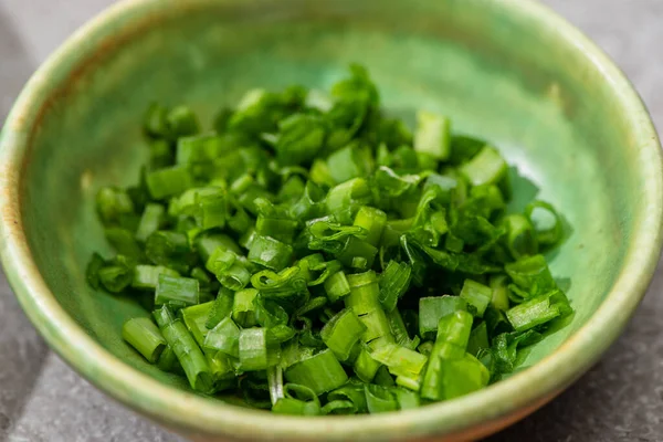 Nahaufnahme frisch geschnittener grüner Zwiebeln in Schüssel auf grauer Betonoberfläche — Stockfoto