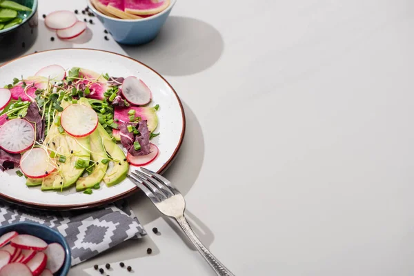 Salada de rabanete fresco com verduras e abacate na superfície cinza com guardanapo e garfo — Fotografia de Stock