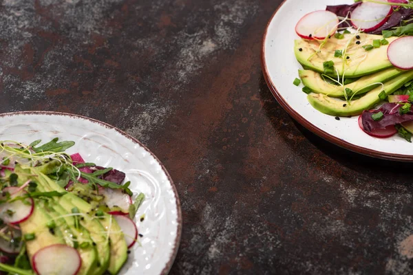 Fresh radish salad with greens and avocado on plates on weathered surface — Stock Photo