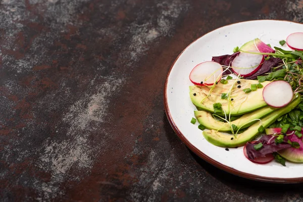 Fresh radish salad with greens and avocado on plate on weathered surface — Stock Photo