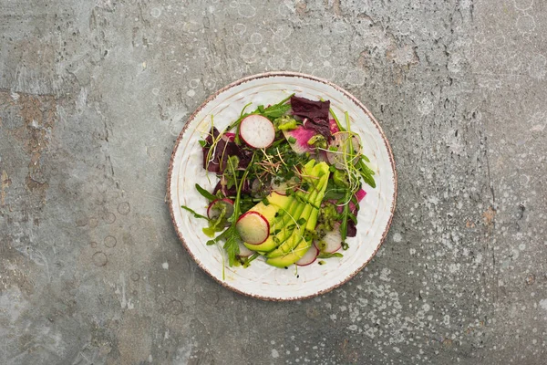 Vista dall'alto di insalata di ravanello fresca con verdure e avocado sulla superficie di cemento grigio — Foto stock