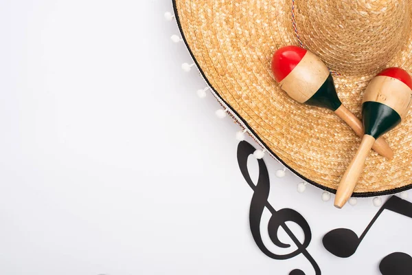 Vista dall'alto di sombrero e maracas vicino a note musicali tagliate su sfondo bianco — Foto stock