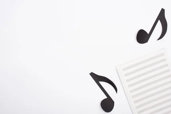 Top view of music book and paper cut notes on white background — Stock Photo