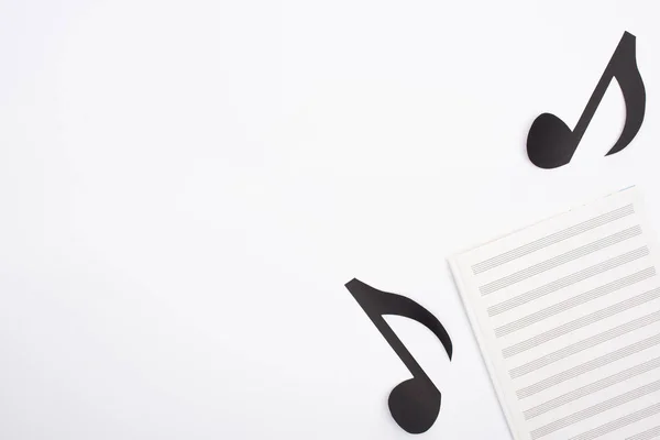 Vista dall'alto del libro musicale e delle note tagliate su sfondo bianco — Foto stock