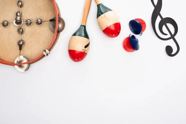 Vue du dessus du papier coupée note de musique, maracas, castagnettes et tambourin sur fond blanc — Photo de stock