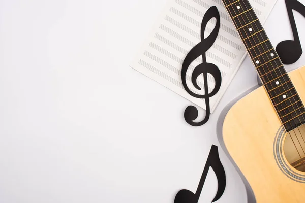 Vista superior de notas de corte de papel com livro de música e guitarra acústica sobre fundo branco — Fotografia de Stock