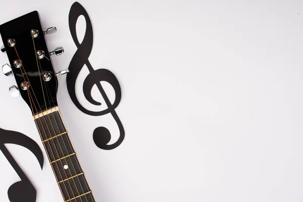Vista superior de papel cortado notas musicales y guitarra acústica sobre fondo blanco - foto de stock