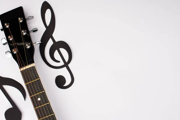 Vista dall'alto di note musicali e chitarra acustica su sfondo bianco — Foto stock