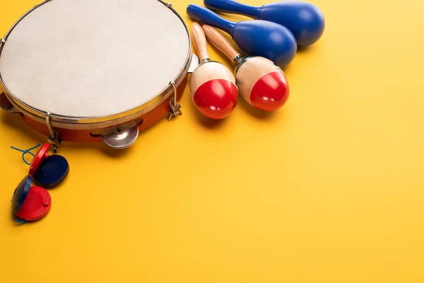 Maracas coloridas e azuis de madeira com pandeiro e castanholas sobre fundo amarelo — Fotografia de Stock