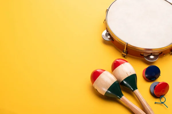 Maracas coloridas de madera con pandereta y castañuelas sobre fondo amarillo - foto de stock